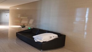 A modern hotel lobby with a black sofa, a small table with a plant, and a large mirror on the wall. - Xiamen IMAY Designer Seaview Apartment (Shimao Twin Towers Branch) (Xiamen)