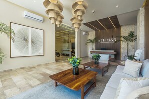 Un vestíbulo moderno con mostrador de recepción, muebles de madera y plantas en macetas.