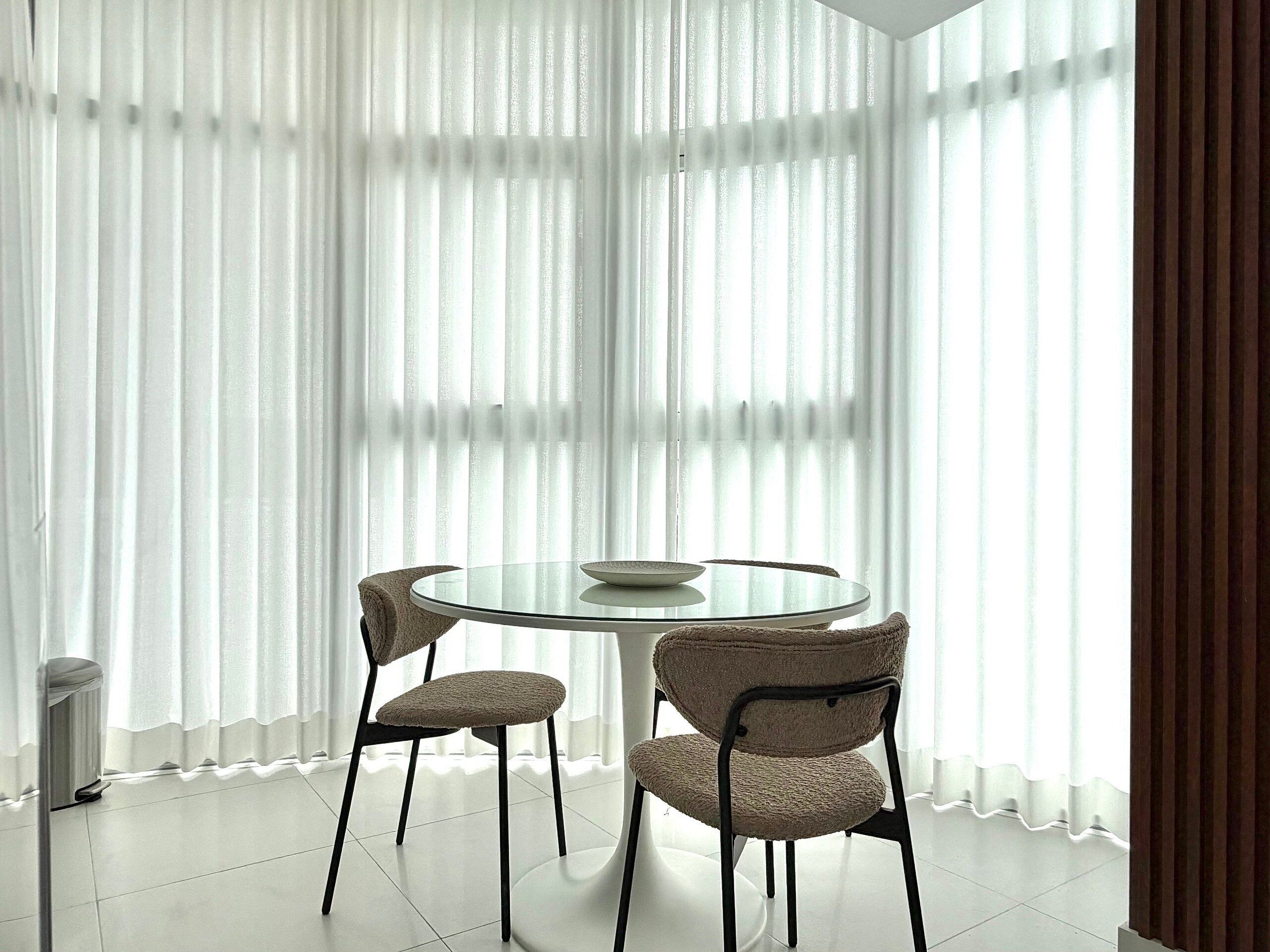 A dining area with a round glass table, two chairs, and a white plate.