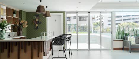 Een moderne receptie met een balie, barstoelen en een grote schuifglazen deur naar een buitenbalkon.