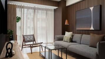 A modern living room with a sofa, a glass coffee table, a wicker chair, a flat-screen TV, and a large abstract painting on the wall.