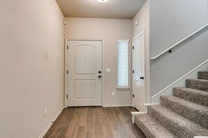 Staircase leads to a closed door at the end of the hallway.