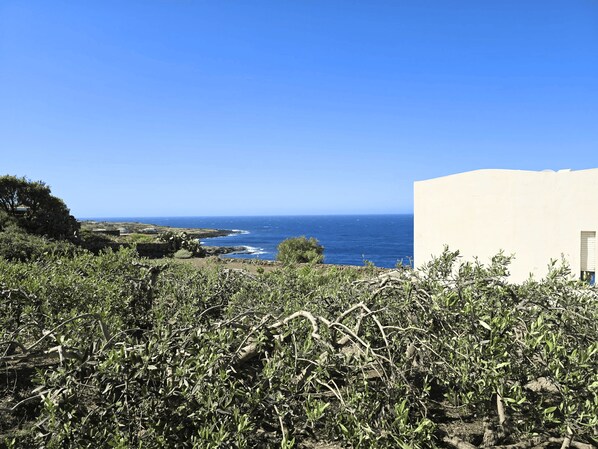 A coastal landscape with a view of the sea, rocky terrain, and a building with a door. - Dammuso - Campobello - RENT'CA (Pantelleria)