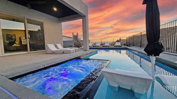 Une piscine sur le toit, avec un jacuzzi, des chaises longues et une vue imprenable sur le coucher de soleil.