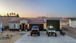 Une allée menant à une maison, avec un garage, un VUS garé et une moto.