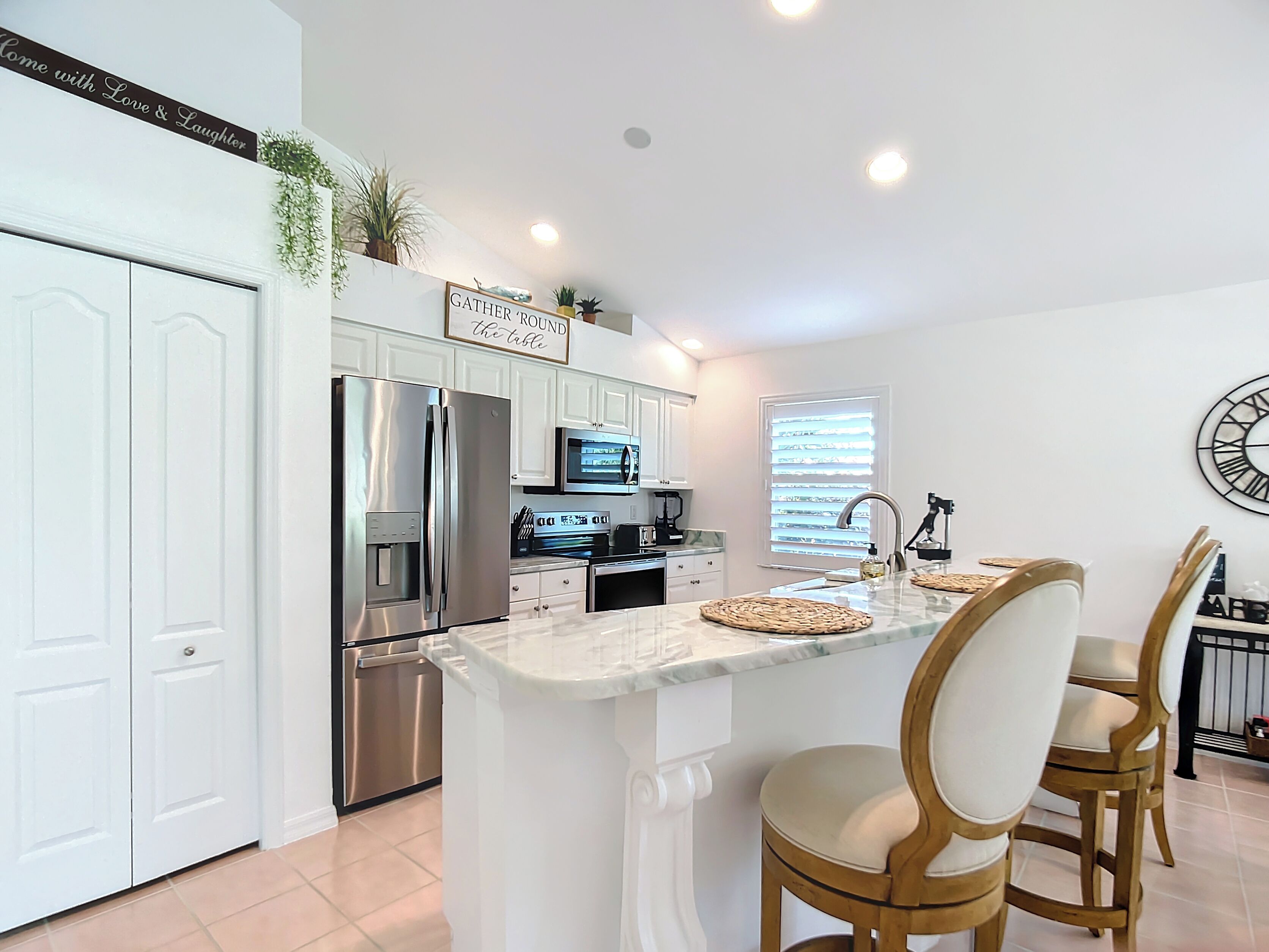 A modern kitchen with white cabinetry, stainless steel appliances, and a central island with bar stools.