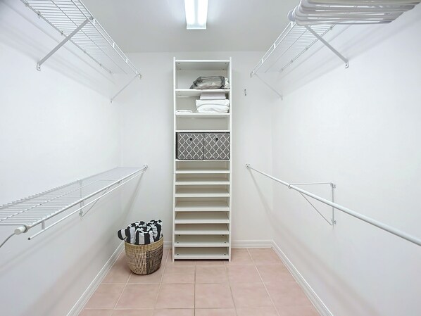A walk-in closet with open shelving, a hanging rod, and a basket.