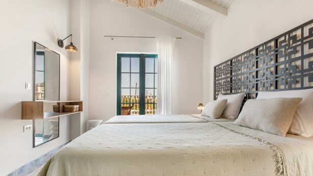 Un dormitorio con una cama grande, un espejo, un estante en la pared, una ventana con cortinas y un panel decorativo.