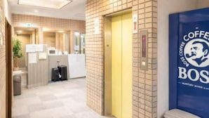 Un vestíbulo de hotel con mostrador de recepción, un cubo de basura y un anuncio de café en la pared.