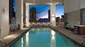 A swimming pool with lounge chairs and a view of a cityscape at dusk. - Your Terrace Your Bay Your Moment Pool Gym (Miami)
