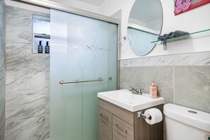 A bathroom with a glass door, a sink, a toilet, and a mirror. - Quiet Miami Oasis Fast Wi-fi Free Parking (Miami)