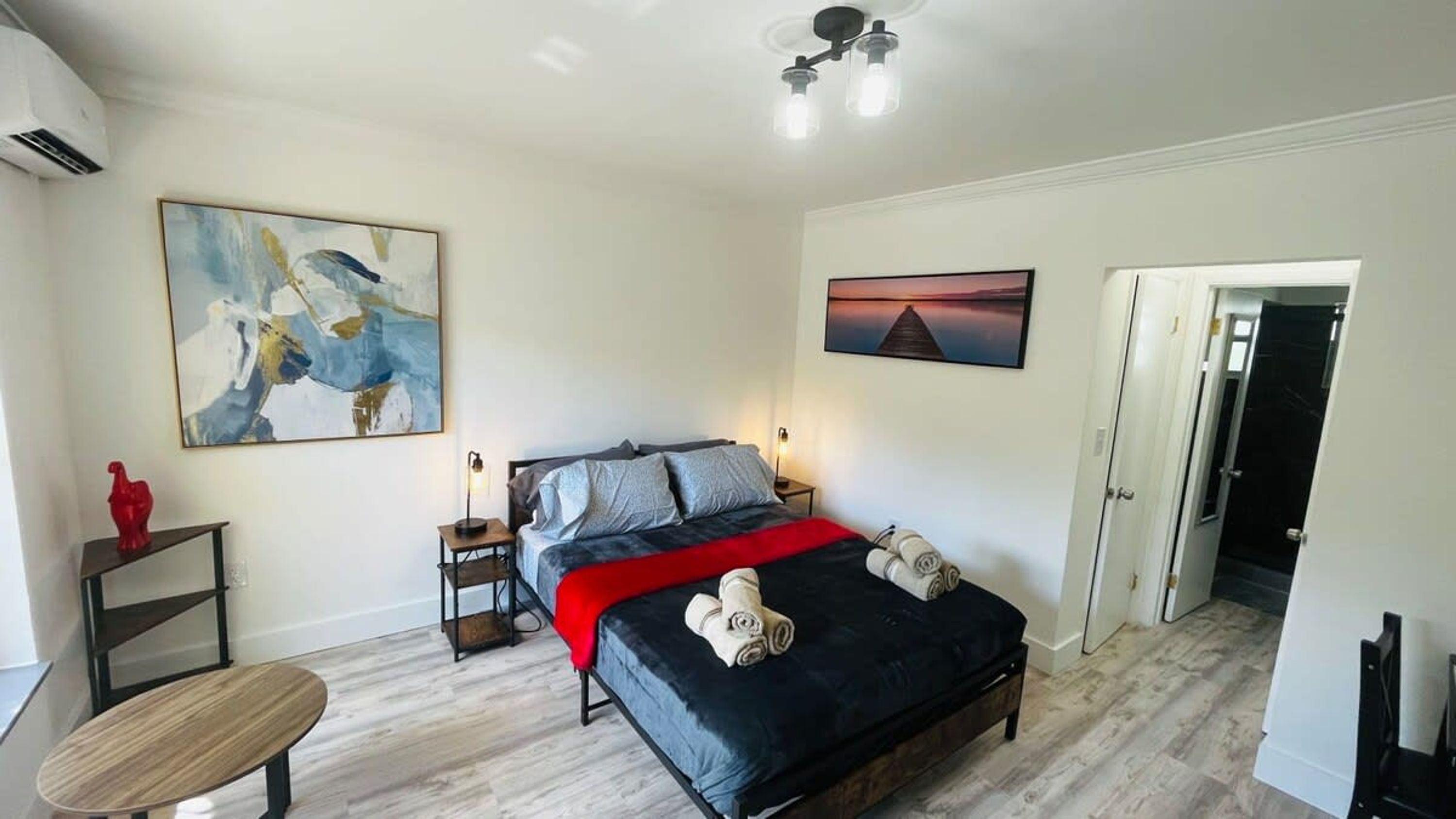 A bedroom with a bed, a nightstand, a chair, and artwork on the walls.