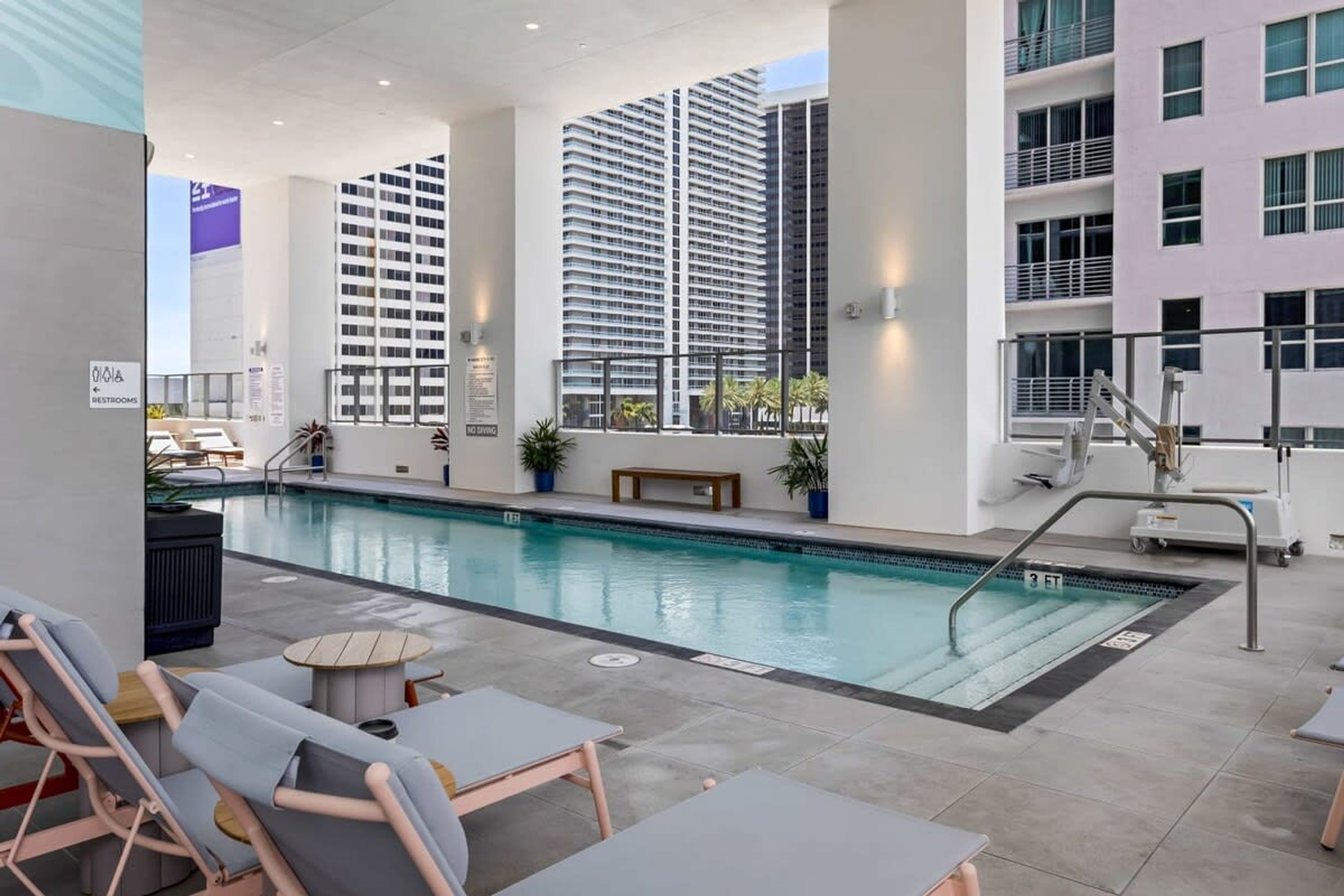 A pool area with lounge chairs and a sign indicating restrooms.