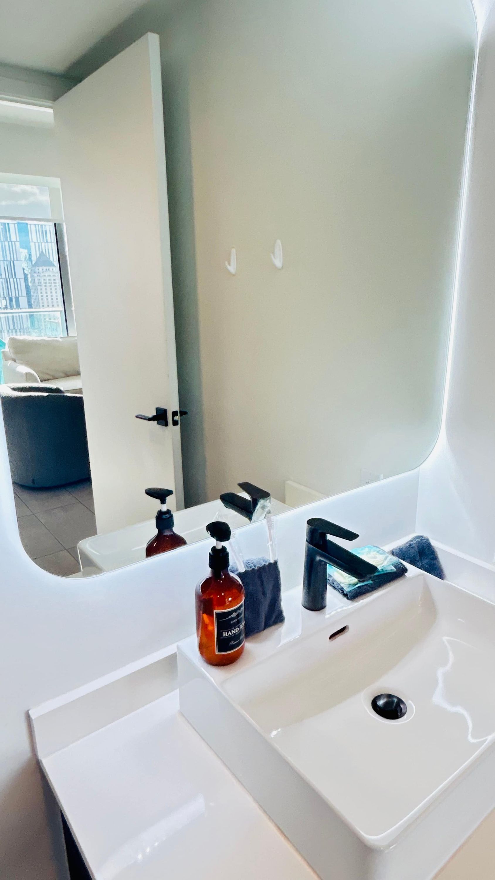 Un bagno moderno con un lavandino bianco, un erogatore di sapone e un asciugamano.
