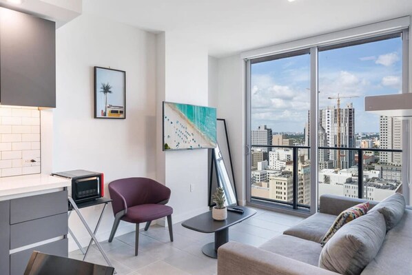 Un apartamento moderno con cocina, comedor, sala de estar y un amplio balcón con vistas a la ciudad.