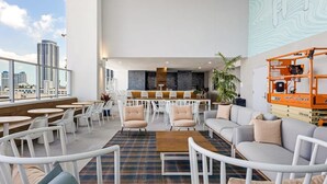 Terraza en la azotea con zonas de estar, bar y vistas a la ciudad.