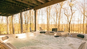 Un jacuzzi con muelle de madera y vista a árboles sin hojas.