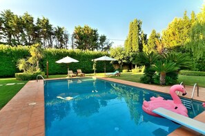 Relax by the clear pool surrounded by lush greenery and lounge under shaded umbrellas.