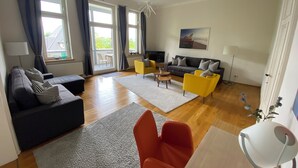 A living room with a sofa, armchairs, a coffee table, and a TV.