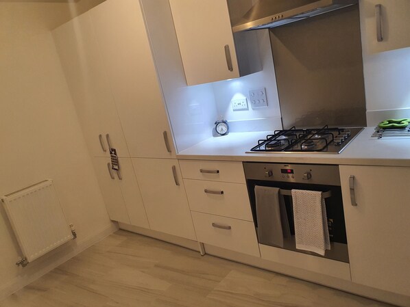 A modern kitchen with white cabinets, a stainless steel stove, and a built-in oven.