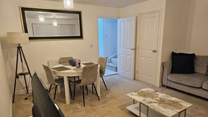 A living room with a dining table, chairs, a sofa, a coffee table, and a lamp. - Charming & Spacious 3-Bed Family Home in Heart of Romsey (Romsey)