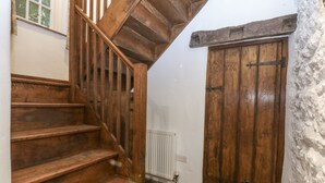 A wooden staircase leading to a room with a stone floor and a wooden door.