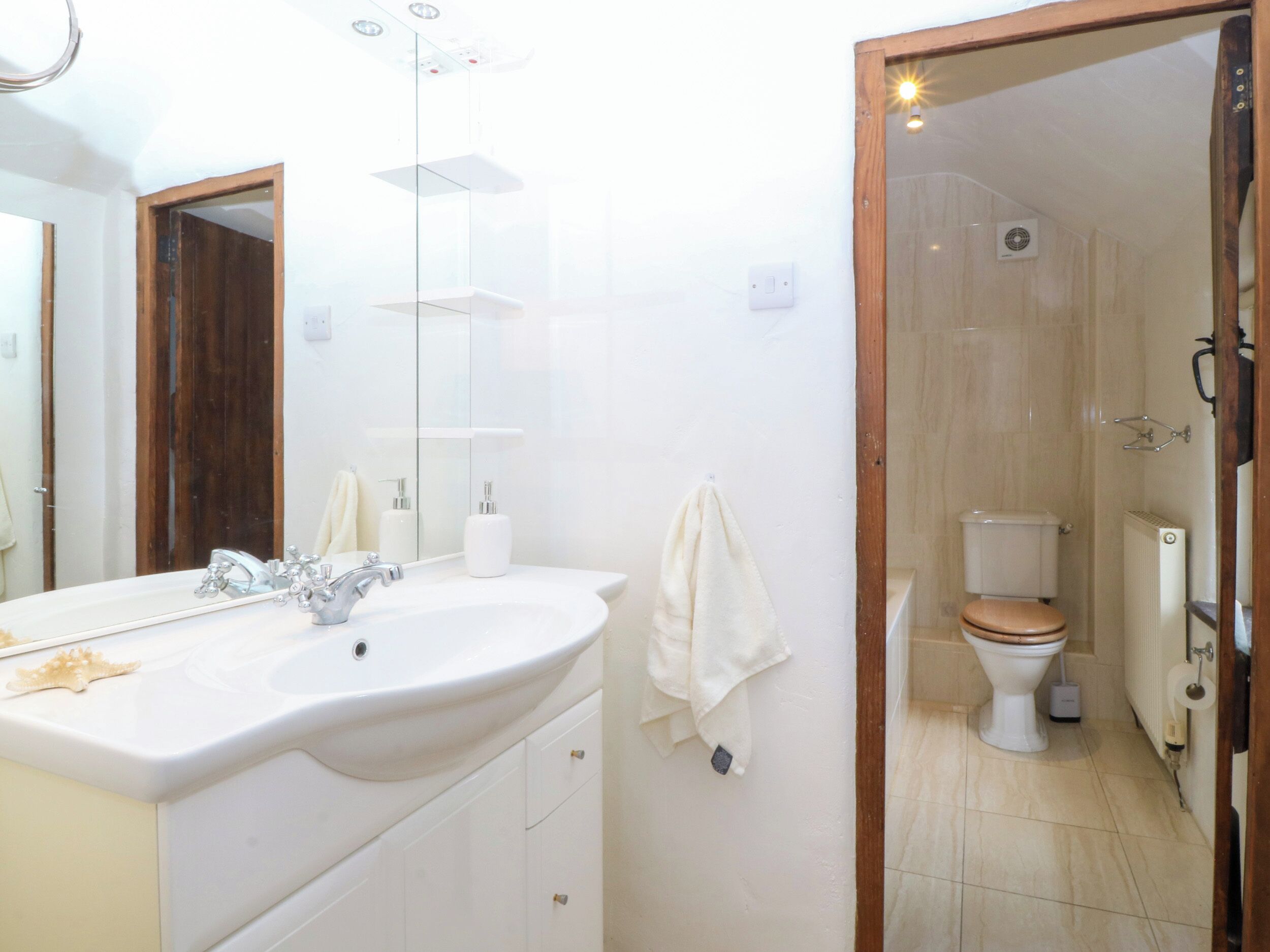 A bathroom with a white sink, a mirror, a towel, a toilet, and a shower area.