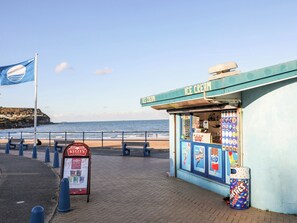 A beachside ice cream cart with a sign reading "ICE CREAM" and a nearby KELLY'S sign. - Tyddyn Iolyn (Tyn-y-Gongl)
