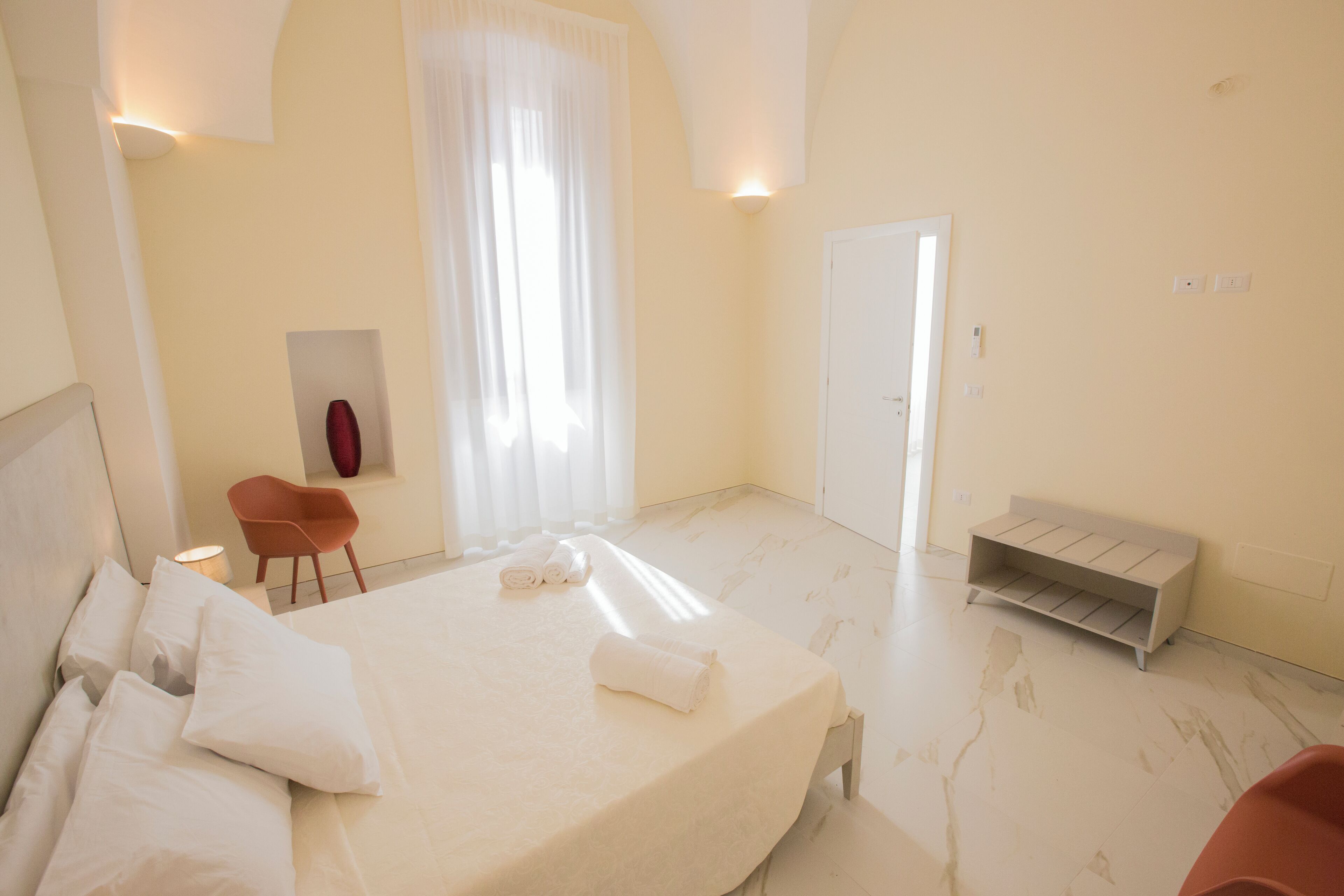 Een hotelkamer met een bed, een stoel, een bank en een deur.