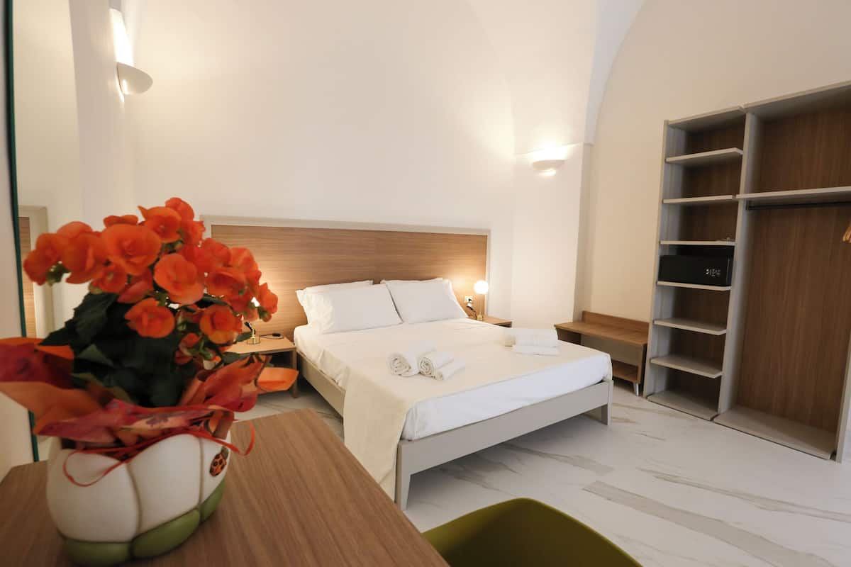 A modern hotel room with a bed, bedside table, and a large wardrobe.