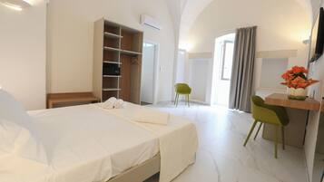 Une chambre d’hôtel comprenant un lit, un bureau, une chaise, une armoire et un téléviseur.