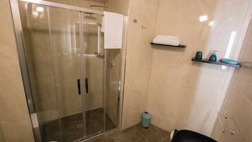 A modern bathroom with a glass-enclosed shower, a toilet, and a sink.