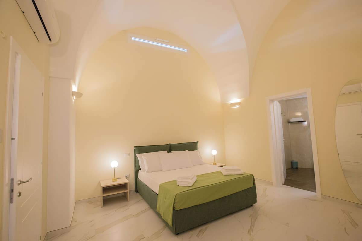 A bedroom with a bed, bedside tables, and a door.