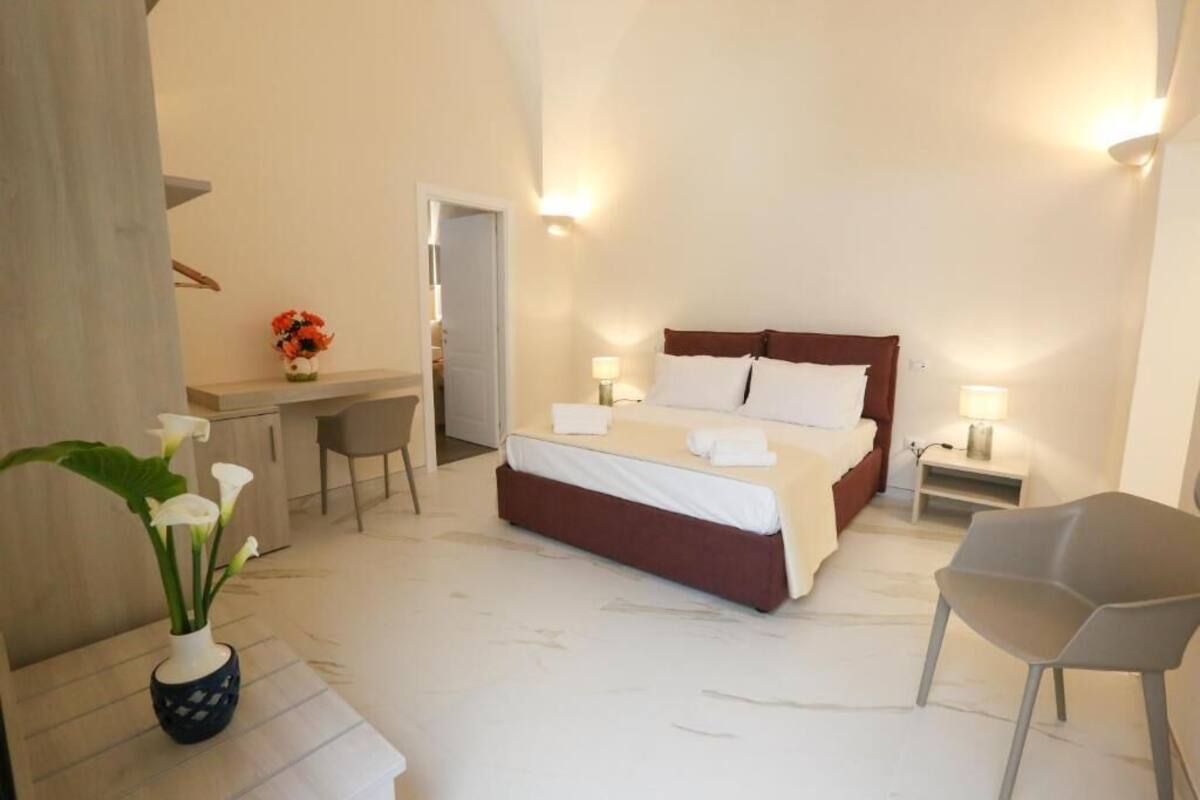 A bedroom with a bed, bedside tables, a desk, and a chair.