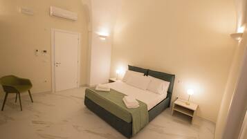 Ein Schlafzimmer mit Bett, Nachttischen, einem Sessel und einer Klimaanlage.