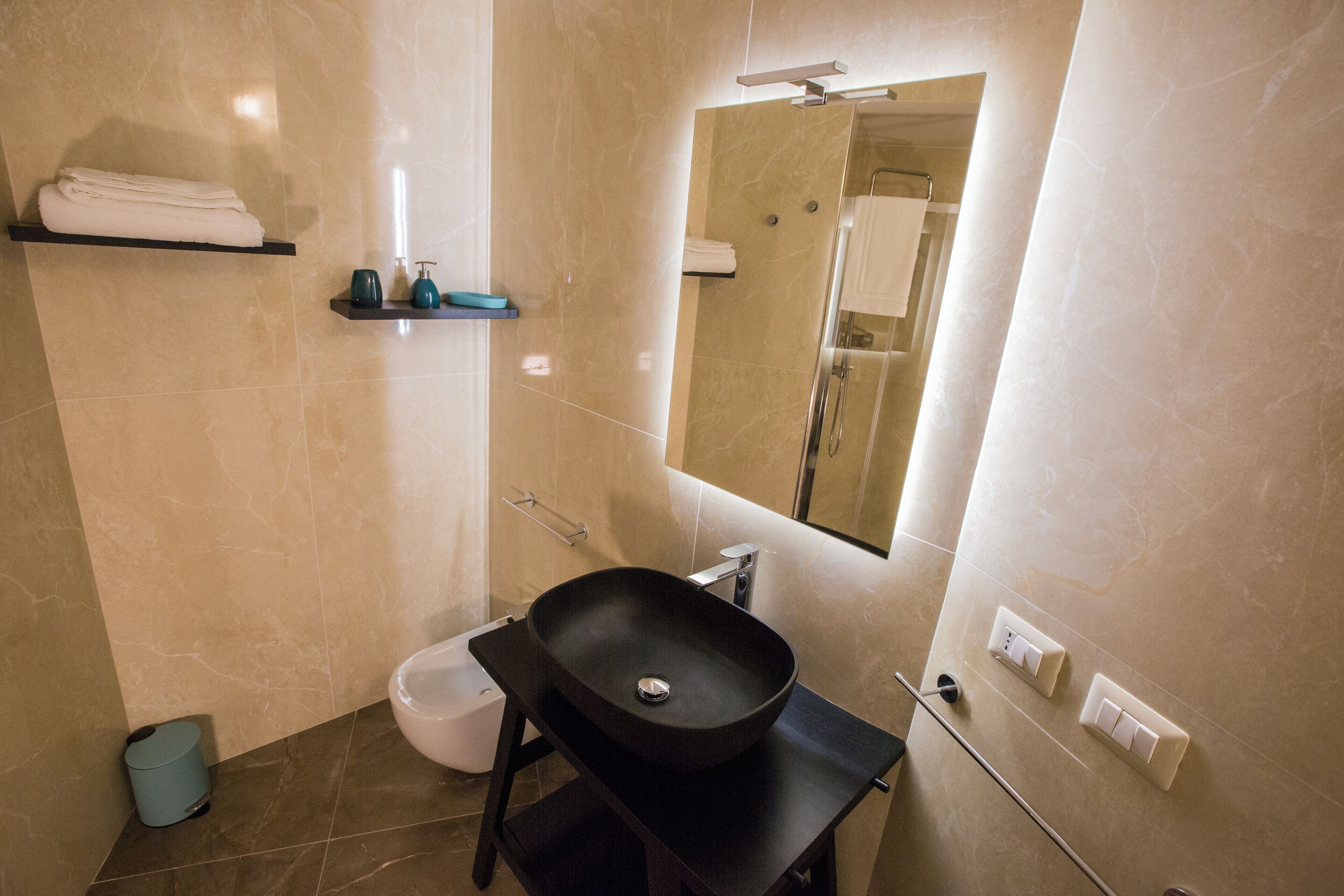 A bathroom with a black sink, a toilet, a towel rack, and a mirror.