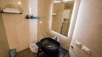A bathroom with a black sink, a toilet, a towel rack, and a mirror.