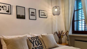 A bedroom with a bed, pillows, a wall-mounted light fixture, and framed pictures.