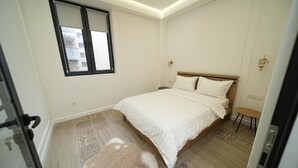 A bedroom with a bed, a window, a small table, and a rug. - Luxury 2BR apartment in the center (Yerevan)
