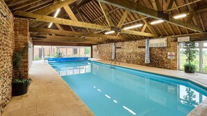 Una piscina interior con techo de madera y paredes de piedra.