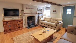 A living room with a fireplace, sofa, wooden coffee table, and TV. - 8 1/2 Church Street (Ambleside)