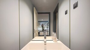 Un baño con un lavabo blanco, un espejo y dos dispensadores de jabón.