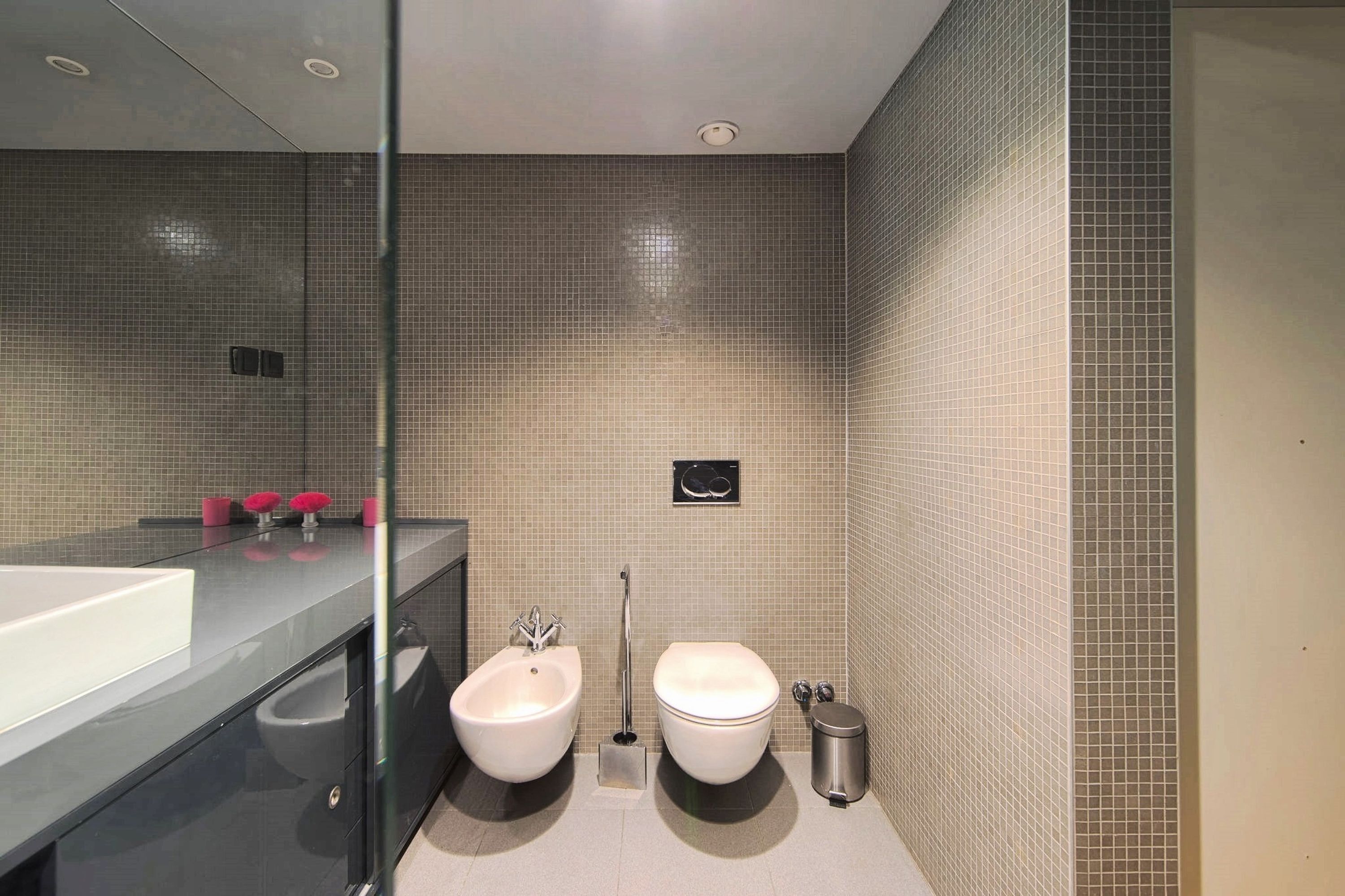 A modern bathroom with a bidet, toilet, and a large mirror.