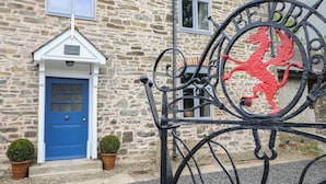 Ein Steinhaus mit einer blauen Tür und einem Schild mit einem roten Drachen.
