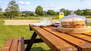 Ein Picknick mit einem Holztisch, einer Kuchenglocke und einer Saftflasche.