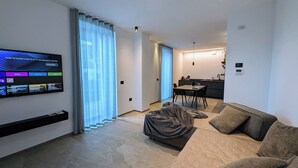 Un salon moderne doté d’un téléviseur à écran plat, d’un canapé, d’une table basse et d’un coin repas avec une table et des chaises.