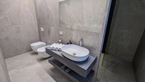 Une salle de bain moderne avec un grand lavabo blanc, un bidet et des toilettes.