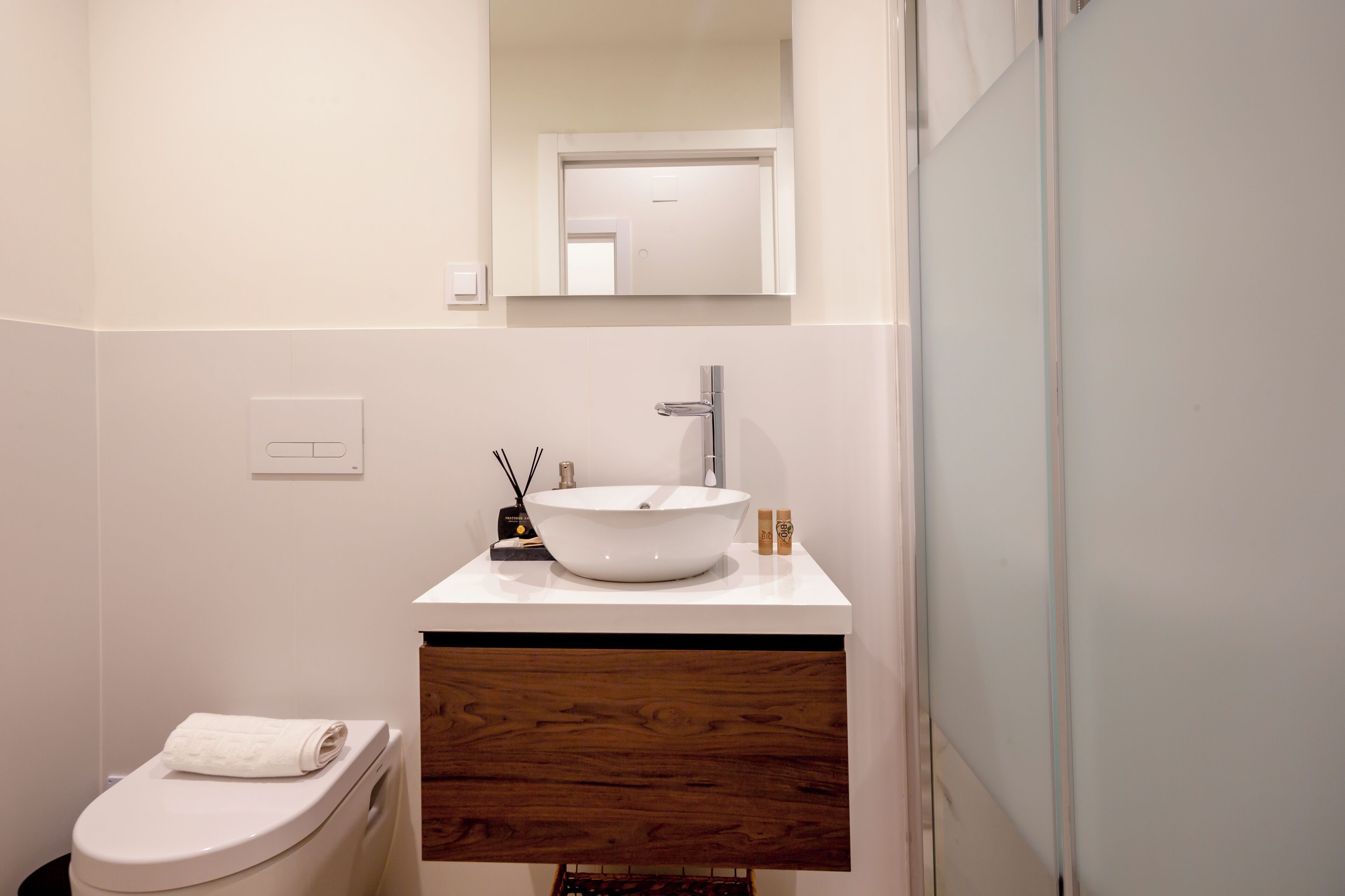 A modern bathroom with a white sink, wooden vanity, and a toilet.