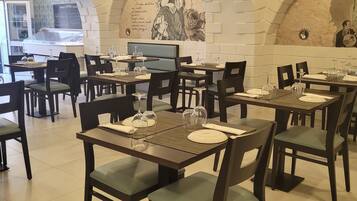 Een restaurant met gedekte tafels, met een modern interieur, gewelfde plafonds en decoratieve muurschilderingen.