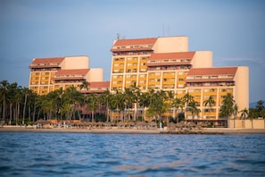 Et hotel med flere etager, beliggende ved stranden, og et poolområde.